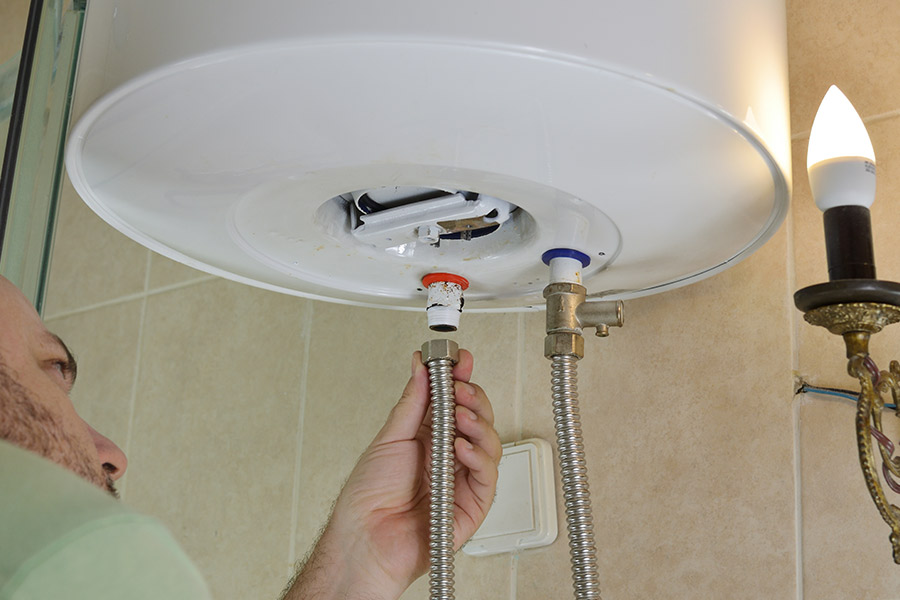 Man installing flexible pipes on a water heater.
